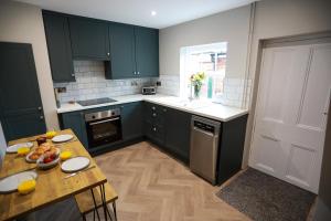 a kitchen with green cabinets and a table with food on it at Auctioneers Cottage in Louth