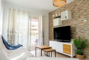 a living room with a tv and a brick wall at Apartamento mediterráneo en pleno corazón de Moraira in Moraira