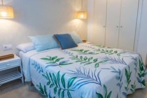 a bedroom with a bed with a blue and white comforter at Apartamento mediterráneo en pleno corazón de Moraira in Moraira