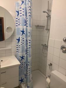 uma casa de banho com um chuveiro com uma cortina azul e branca. em Ferienwohnung Schwitzkowski em Glücksburg