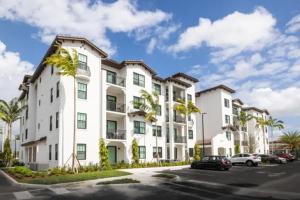 a large white apartment building with cars parked in a parking lot at Miramar 2BR w gym pool wd nr WF MIA-25 in Miramar