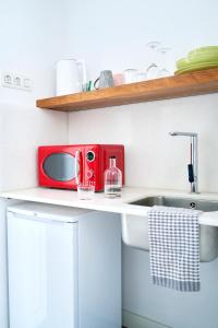 uma cozinha com um lavatório e um micro-ondas vermelho em Eco Boutique Hostal Grau em Barcelona