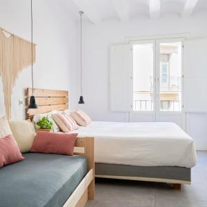 a bedroom with two beds and a bench at Eco Boutique Hostal Grau in Barcelona