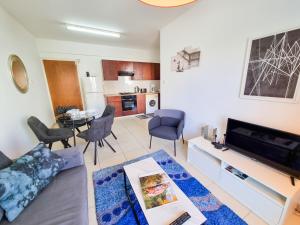 a living room with a couch and a tv and a table at Seaside Heaven Apartment With Pool in Larnaca