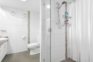 a white bathroom with a shower and a toilet at Cairns Esplanade Apartment in Cairns