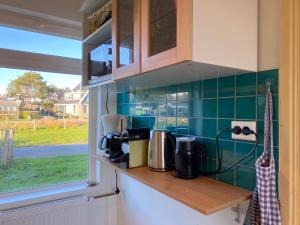 Una cocina con azulejos verdes en la pared y una ventana. en Previnaireweg 16, en Callantsoog