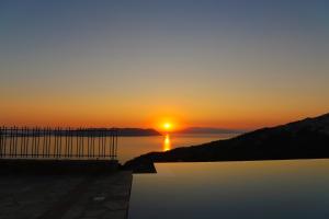 a sunset over a body of water with the sun setting at RODON Luxury Villas in Skopelos Town