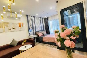 a living room with a bed and a vase of flowers at Căn hộ dịch vụ Homestay Greenbay - Zhomestay in Thượng Thôn