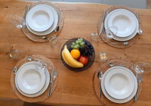 a wooden table with plates and a bowl of fruit at Apartment 4-6 Personen I 80qm I Altstadt I Dachterasse I Parkplatz in Straubing