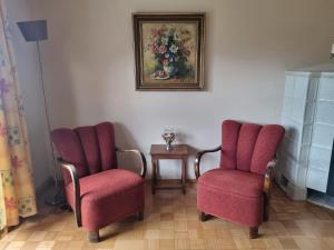 duas cadeiras vermelhas num quarto com um quadro na parede em Ferienwohnung Toni em Freyung