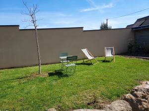 two chairs and a table and a tree in a yard at La Clé du Chesnot in Saint-Quentin-sur-le-Homme