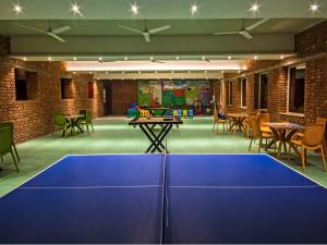 a blue ping pong table in a room with chairs at Kripanidhi Retreat Rajgir in Rājgīr