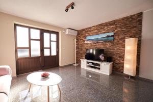un salon avec une télévision sur un mur en briques dans l'établissement Haus Mila, à Pavicini