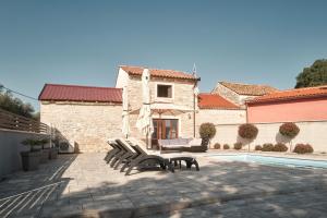 un patio avec bancs à côté d'un bâtiment avec piscine dans l'établissement Haus Mila, à Pavicini