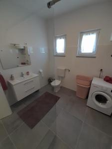 a bathroom with a toilet sink and a washing machine at Dani in Zadar