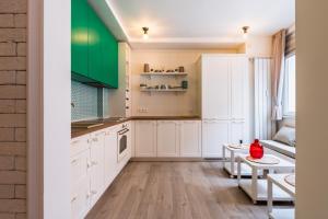 a kitchen with white cabinets and green accents at Doctors Garden - Central&Modern 2BD Flat in Sofia in Sofia