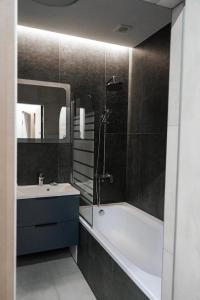 een badkamer met een bad, een wastafel en een douche bij NL group apartments in Kolomiya