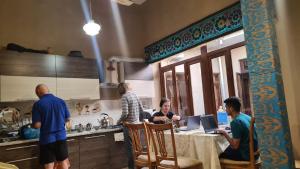 a group of people sitting at a table in a kitchen at Azaliya Hostel in Samarkand