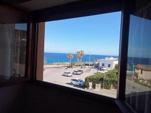 een raam met uitzicht op een parkeerplaats en de oceaan bij Casa freogan in Castelsardo