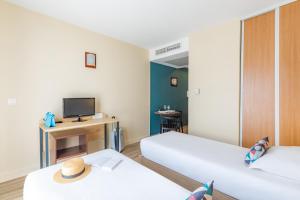 ニースにあるAppart'City Classic Nice Acropolisのベッド2台とテレビが備わる小さな客室です。