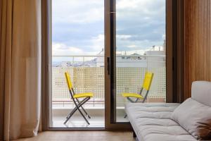 Habitación con 2 sillas amarillas y balcón. en Goudi 4th Floor Greece Apartments, en Atenas
