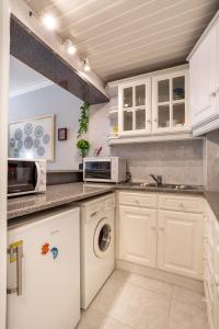 a kitchen with white cabinets and a washer and dryer at JOIVY Vibrant flat with balcony in Costa da Caparica