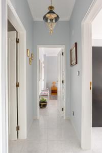 a hallway with white walls and a chandelier at ALTIDO Vibrant flat with balcony in Costa da Caparica