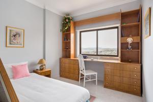 a bedroom with a bed and a desk and a window at ALTIDO Vibrant flat with balcony in Costa da Caparica