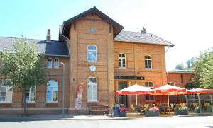 un edificio de ladrillo con mesas y sombrillas delante en Ferienwohnung im Bahnhof Lügde en Lügde