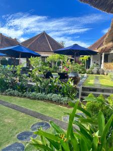 a resort with a garden with blue umbrellas at Asri Villas Bingin in Uluwatu