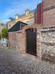een stenen garage met een zwarte deur op een bakstenen gebouw bij Chambre D'hôte Villa Maurice in Étretat