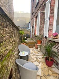 een patio met 2 stoelen en een stenen muur bij Chambre D'hôte Villa Maurice in Étretat