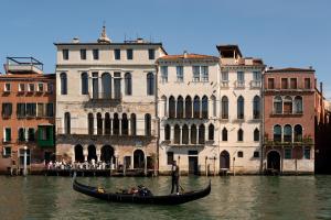 Un uomo in una gondola in acqua vicino agli edifici di The Venice Venice Hotel a Venezia