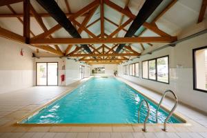 an indoor swimming pool with blue water and wooden ceilings at Glamping Lac d'Orient in Mesnil-Saint-Père