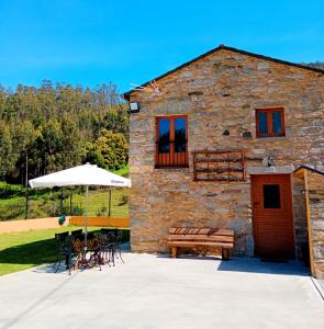 een stenen gebouw met een tafel en stoelen en een parasol bij Casa Carmelo in Viveiro