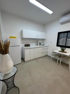 a kitchen with a white refrigerator and a table at צימר פסטורלי בהגושרים in HaGoshrim