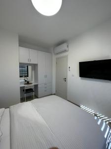 a white bedroom with a bed and a flat screen tv at צימר פסטורלי בהגושרים in Hagoshrim