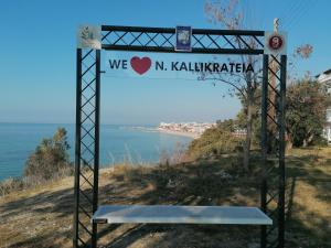 a sign on the side of a hill with a bench at Crystal Blue Apartments in Nea Kalikratia