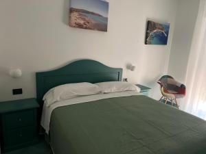 una camera con un letto verde e una sedia di B&B Residence Eco Del Mare a Palinuro