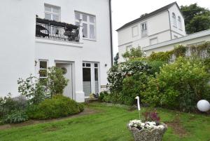 a white house with a balcony and a yard at fewo1846 - Pauline - zauberhafte Wohnung für 2 Personen mit Terrasse und Garten in Glücksburg