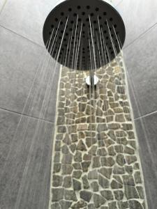 a shower with a stone floor and a shower head at Asri Villas Bingin in Uluwatu