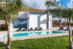 une villa avec une piscine et des palmiers dans l'établissement Villa Sikania Seaview Scopello, à Castellammare del Golfo
