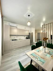 eine weiße Küche mit einem Tisch und grünen Stühlen in der Unterkunft Tanya Apartments Nord10 in Mamaia Nord – Năvodari