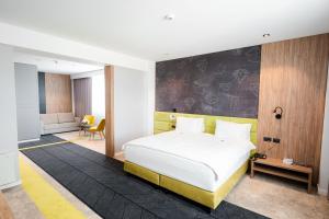 a bedroom with a white bed and a black and yellow wall at Mandachi Hotel & SPA in Suceava