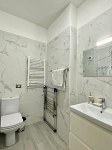 ein weißes Bad mit einem WC und einem Waschbecken in der Unterkunft Tanya Apartments Nord10 in Mamaia Nord – Năvodari