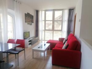 uma sala de estar com um sofá vermelho e uma mesa em Alojamiento rural El Refugio em Tudanca