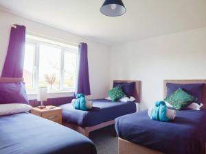 um quarto com três camas com lençóis azuis e uma janela em Lancaster House em Lincoln