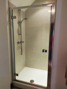 a shower with a glass door in a bathroom at The Retreat in Tibenham