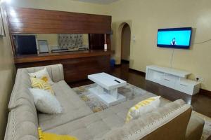 een woonkamer met een bank en een tv bij A cosy Mustard Haven-Shanzu in Mombasa