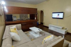 een woonkamer met een bank en een flatscreen-tv bij A cosy Mustard Haven-Shanzu in Mombasa